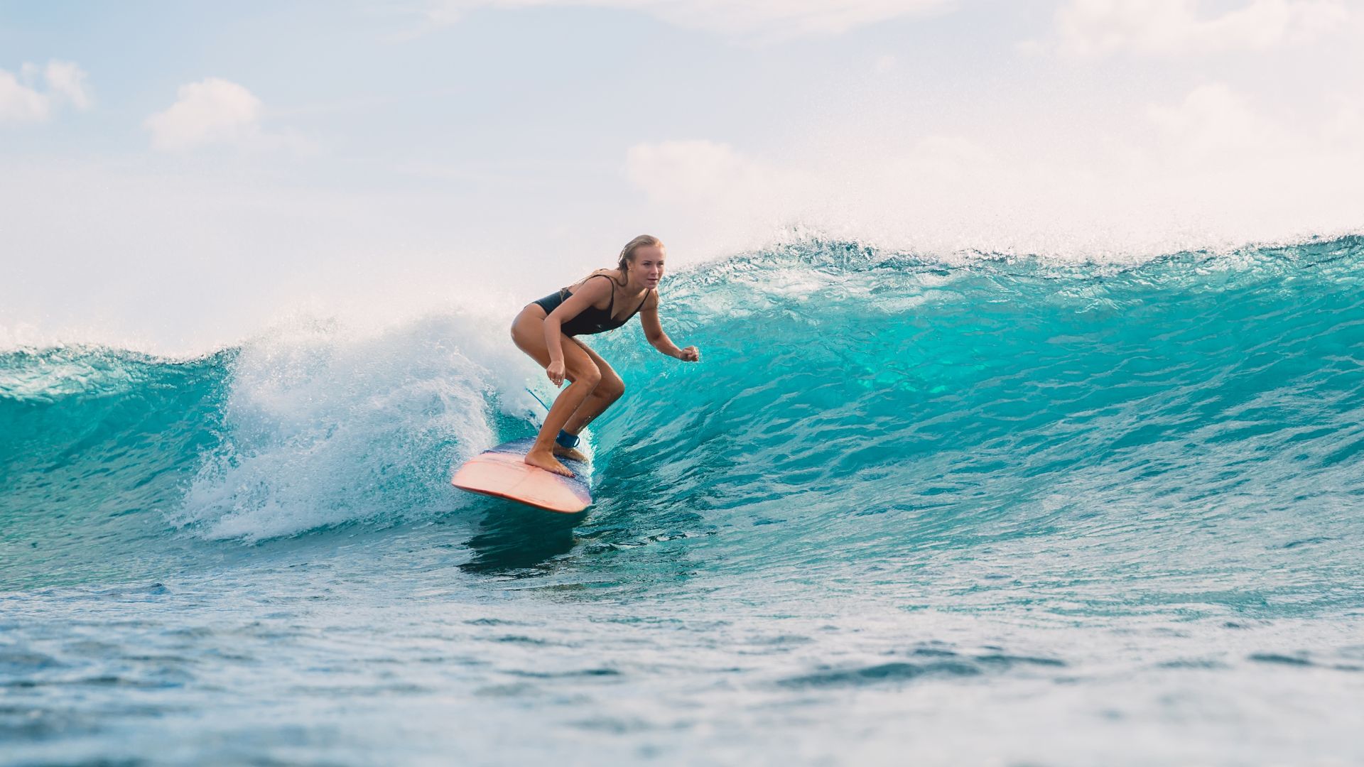 Une surfeuse sur la vague turquoise