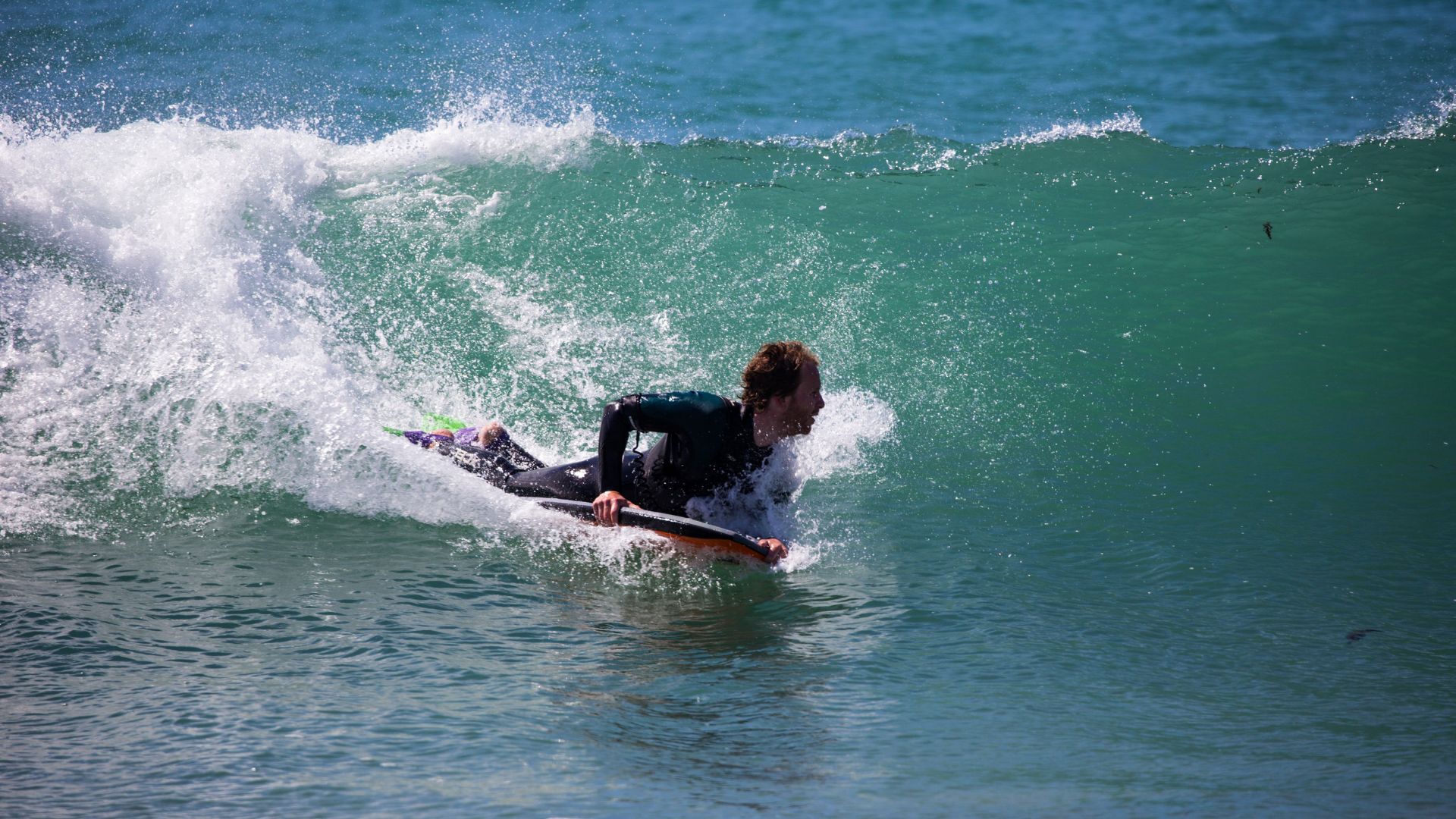 Un bodyboarder surfe une vague